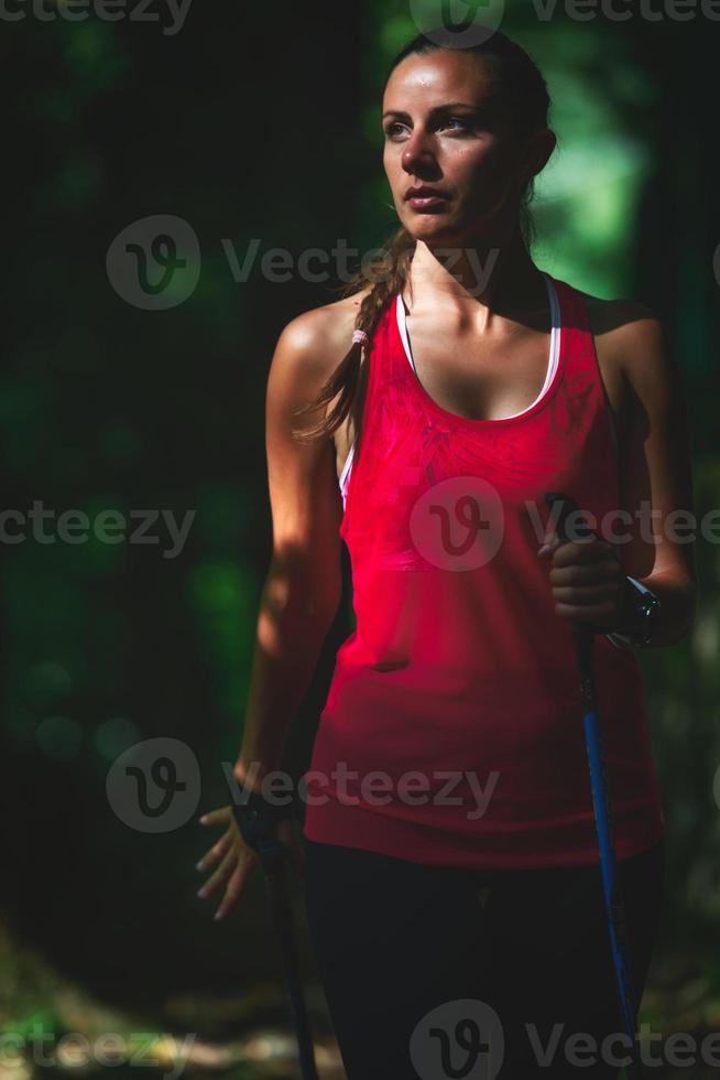 sportieve vrouw die nordic walking in het bos beoefent foto