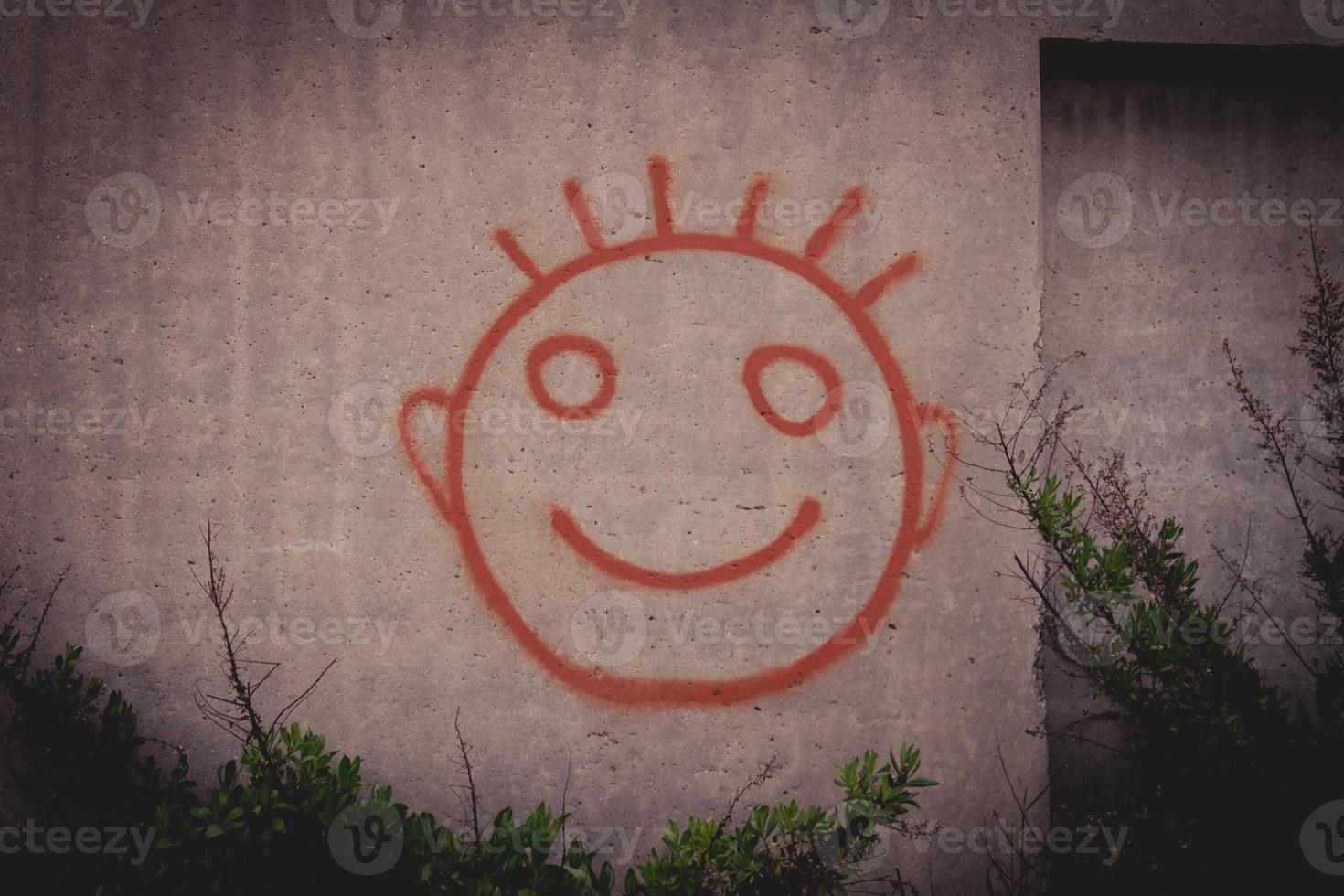 graffiti schilderij van rode blije smiley op een betonnen muur foto
