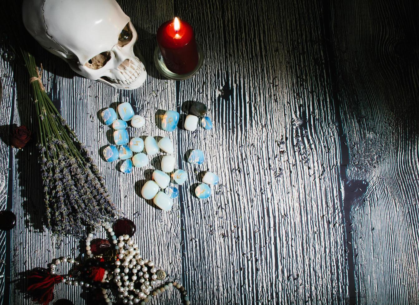 houten tafel met occulte attributen. runenstenen, kaarsen, foto