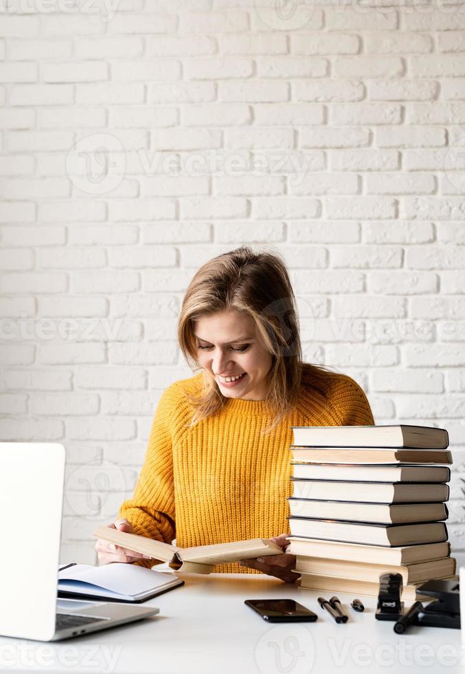 jonge lachende vrouw in gele trui studeren lezen van een boek foto