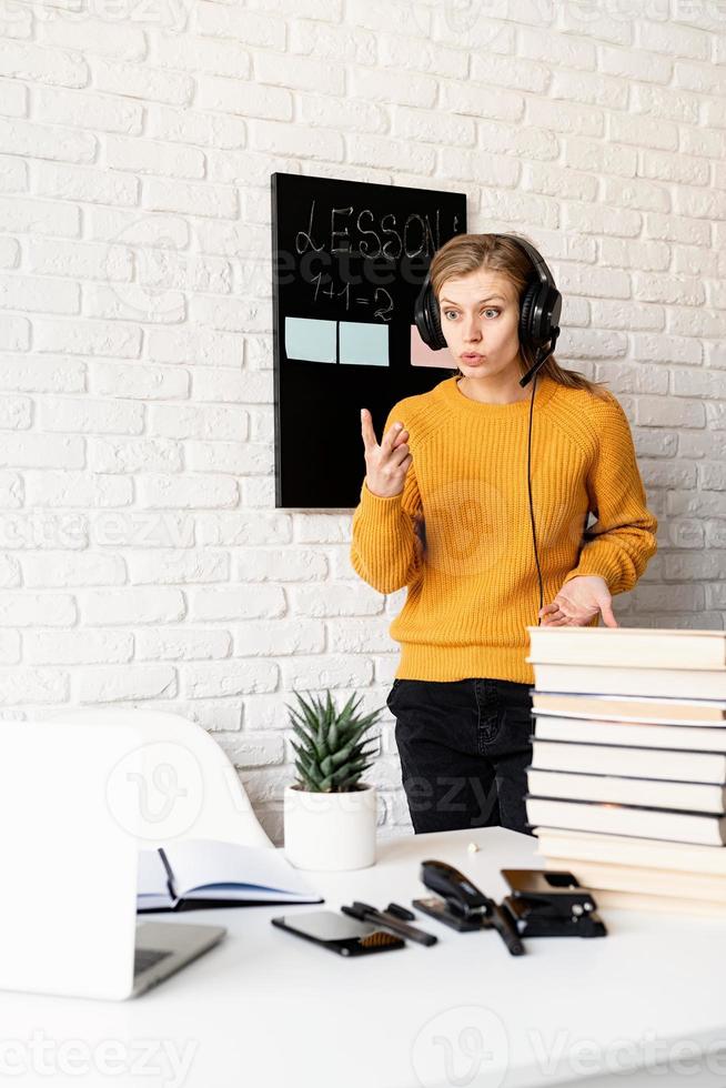 vrouw met koptelefoon die online lesgeeft met behulp van videochat op laptop foto