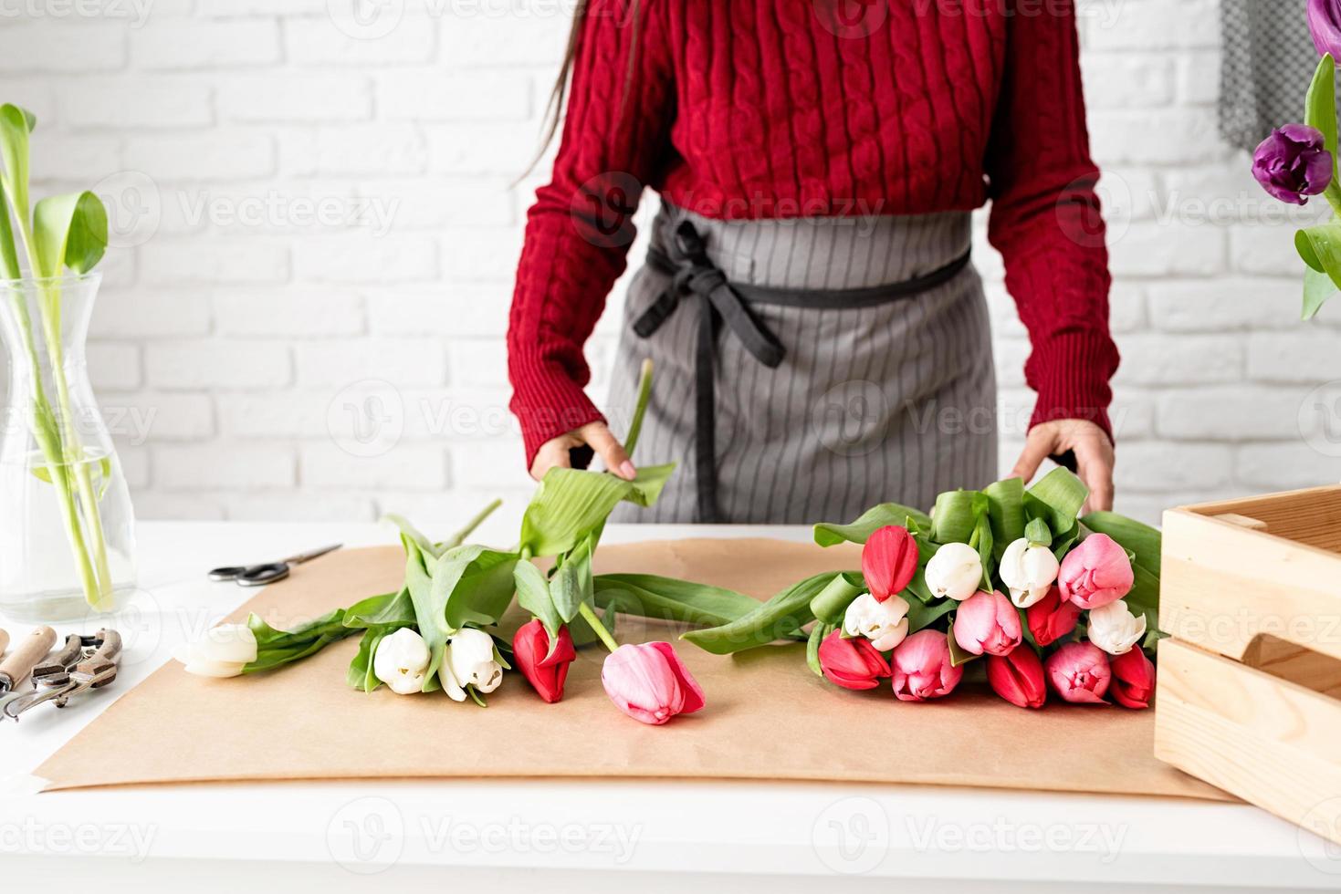 vrouwelijke bloemist die een boeket verse kleurrijke tulpen maakt foto