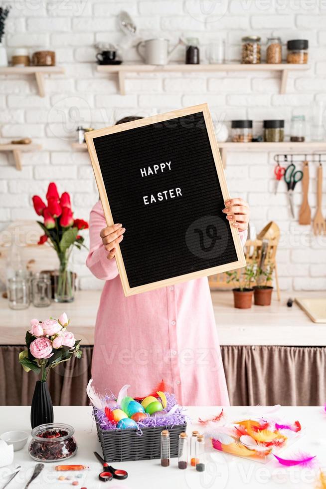 vrouw in roze jurk met zwarte letterbord met woorden vrolijk pasen foto