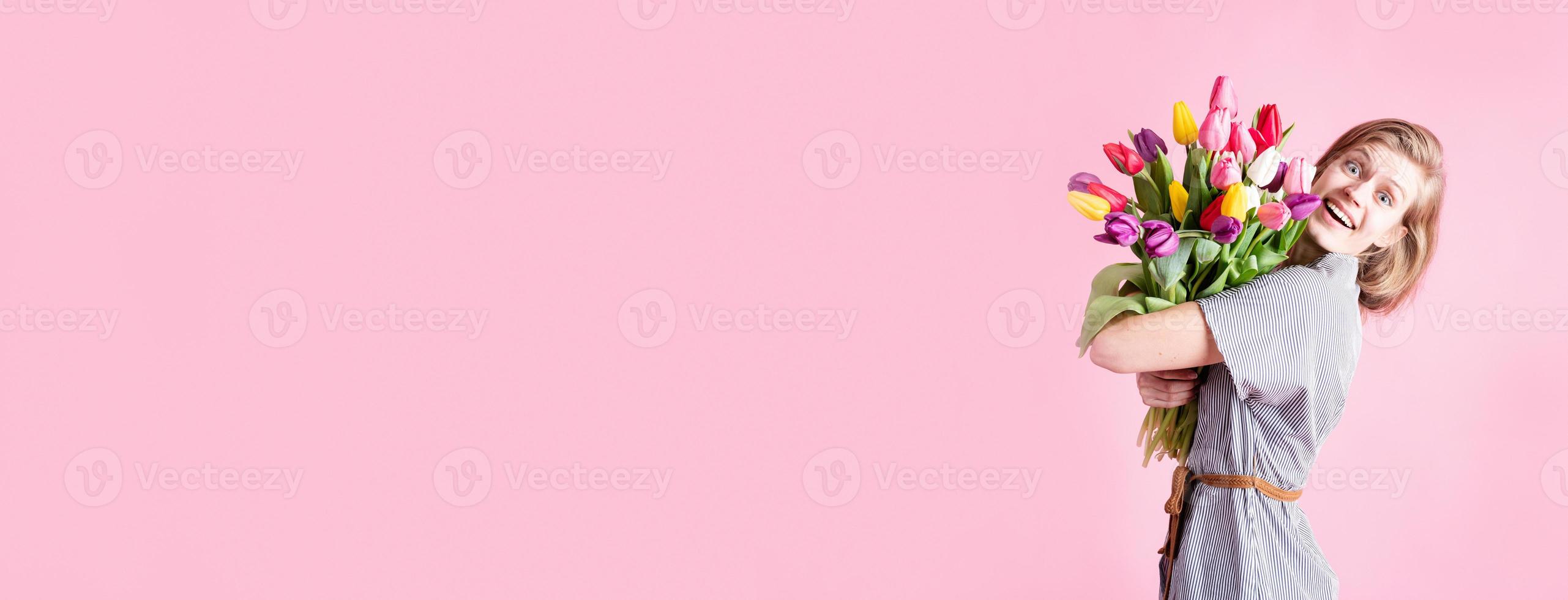 vrouw met boeket verse tulpen geïsoleerd op roze background foto