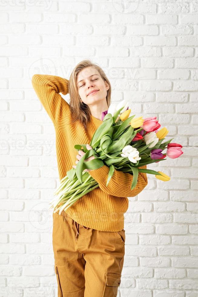gelukkige mooie vrouw in gele kleren met boeket tulpen foto