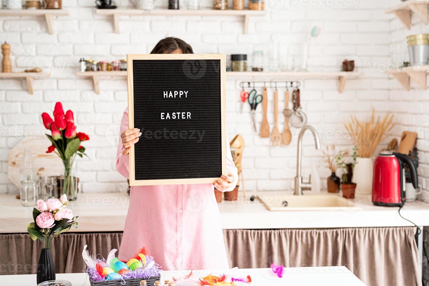 vrouw in roze jurk met zwarte letterbord met woorden vrolijk pasen foto