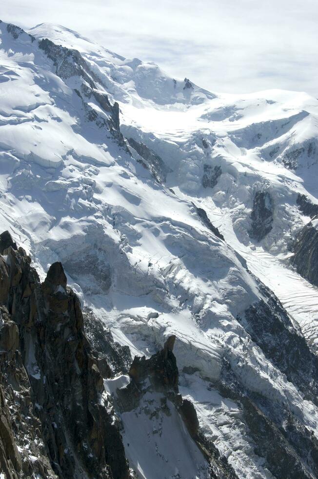 twee mensen zijn wandelen omhoog een berg met sneeuw gedekt bergen foto