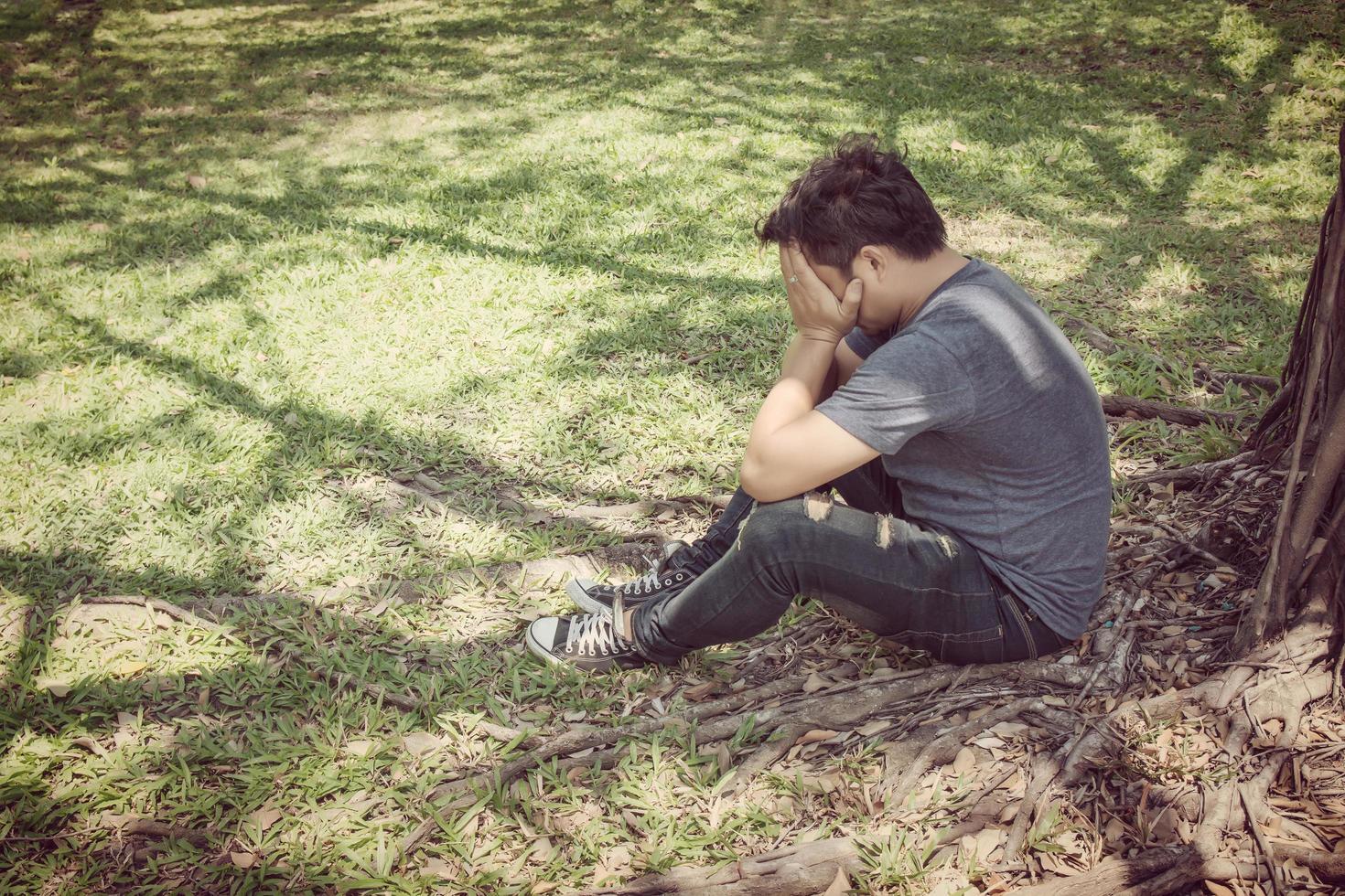 trieste jonge man zit in het park foto