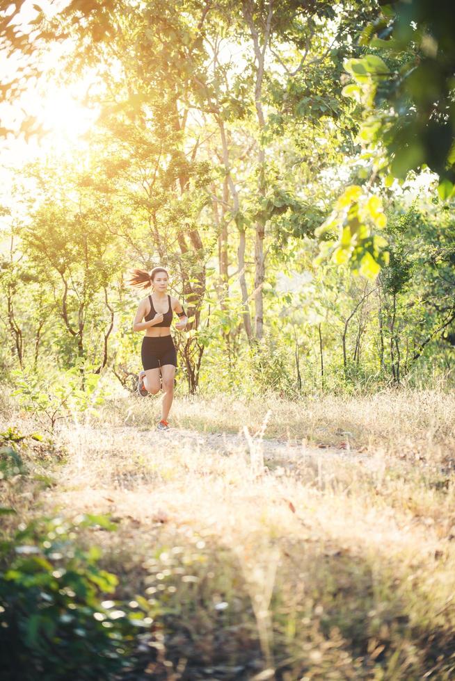 jonge vrouw joggen op landelijke weg in de bosnatuur. foto