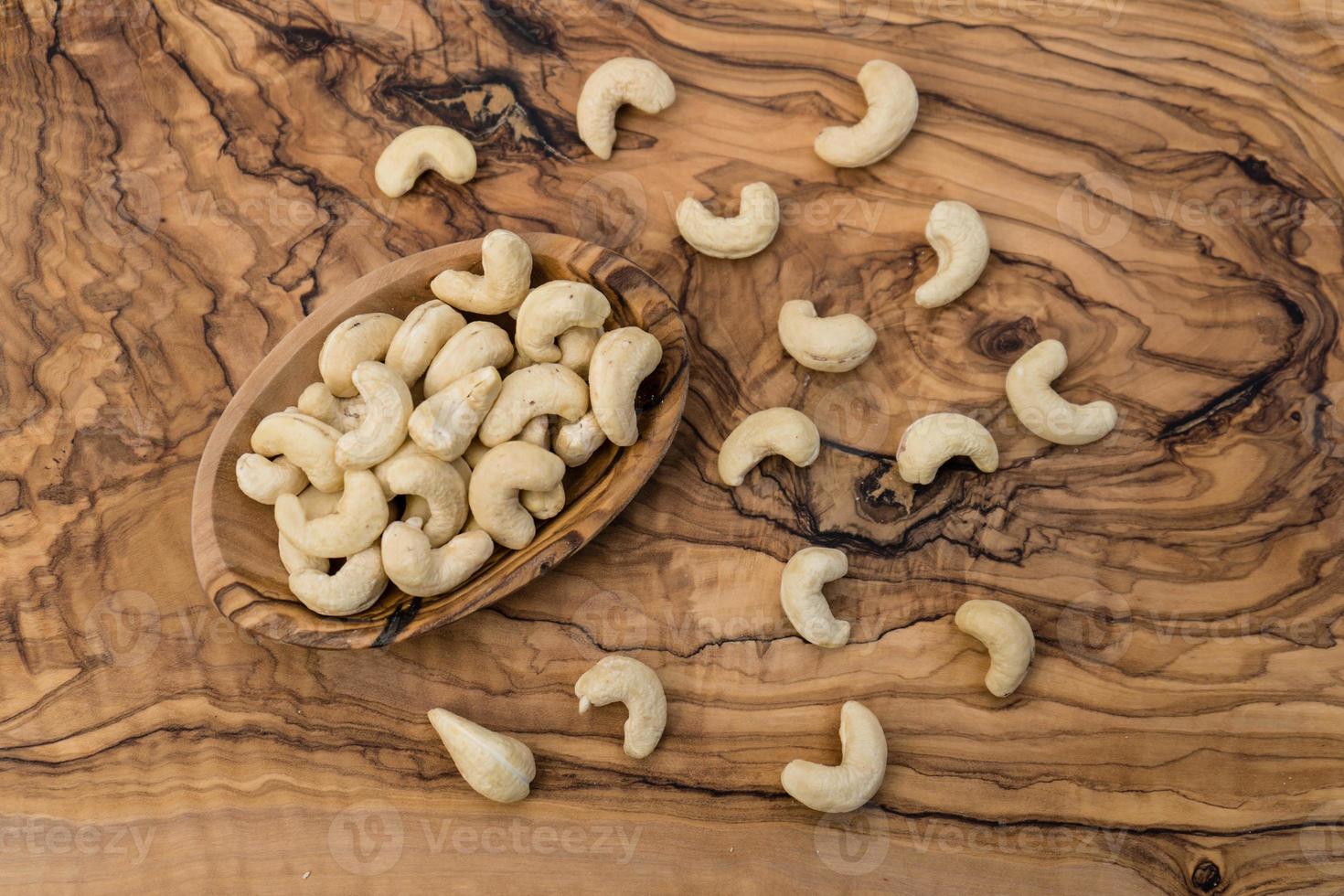 een stapel cashewnoten op olijfhout foto