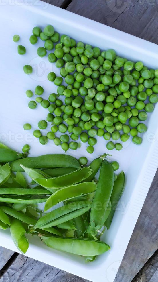 groene erwten zitten in een zak op een wit dienblad. verse groenten oogsten foto