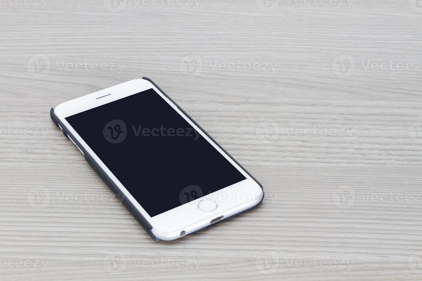 slimme telefoon met leeg scherm liggend op grijze houten tafel foto