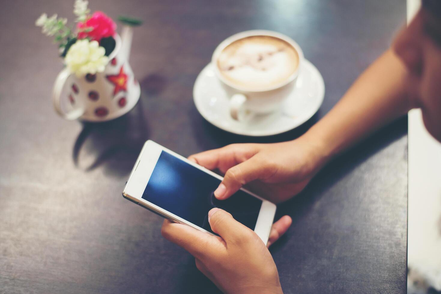 close-up van vrouw handen sms'en met haar mobiel bij coffeeshop. foto