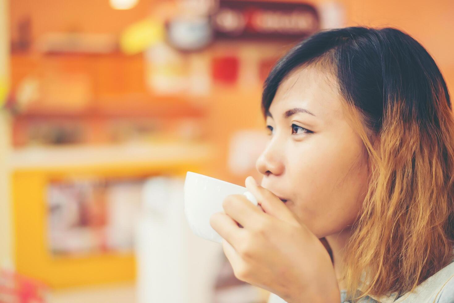 jonge mooie vrouw die hete cappuccino-koffie drinkt in café. foto