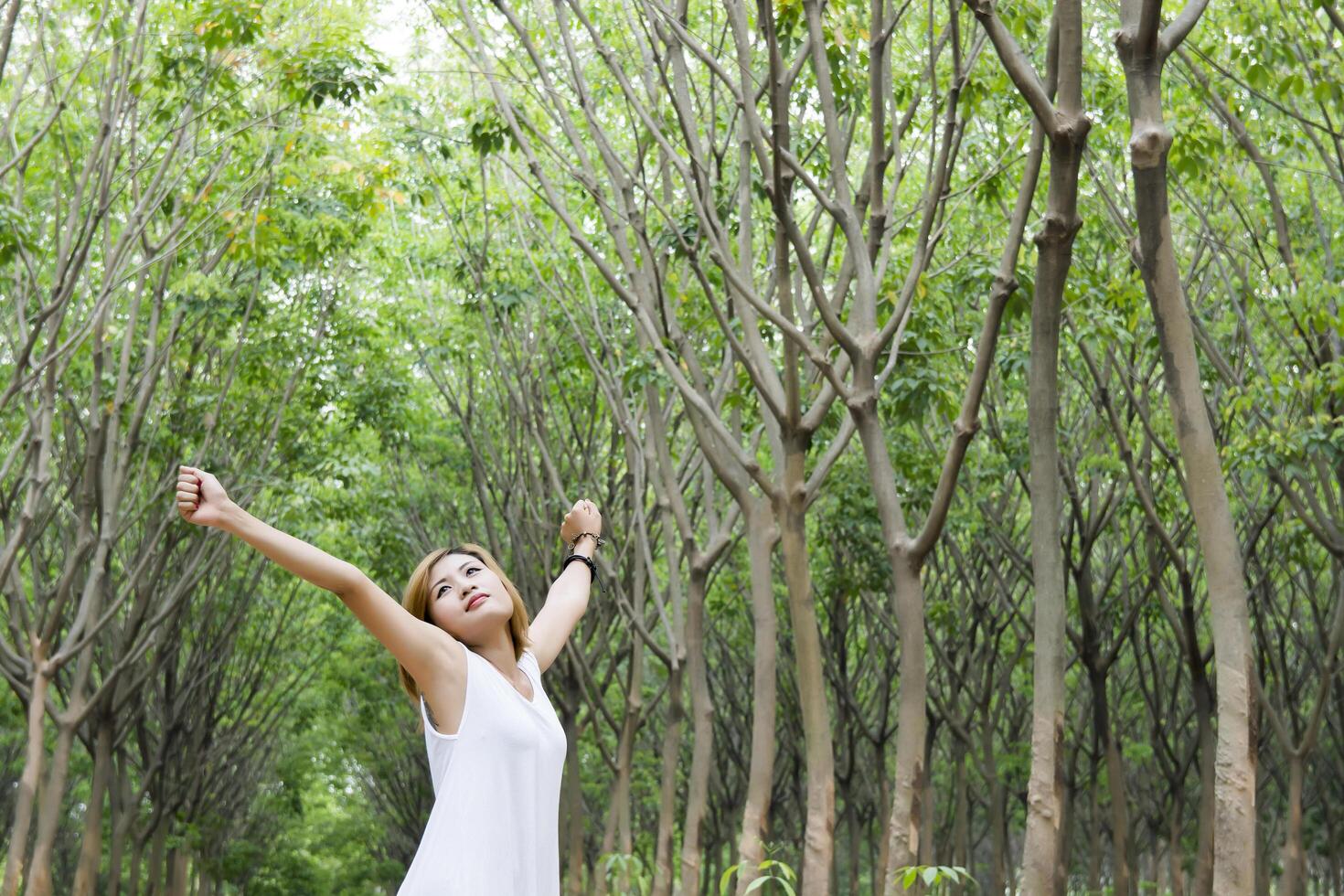 jonge mooie vrouw hief de armen op en geniet van het frisse in het groene bos. foto