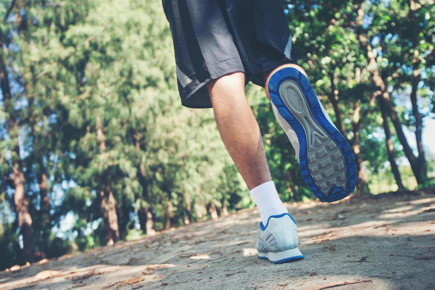 close-up voet van jonge runner man loopt langs de weg in het park. foto