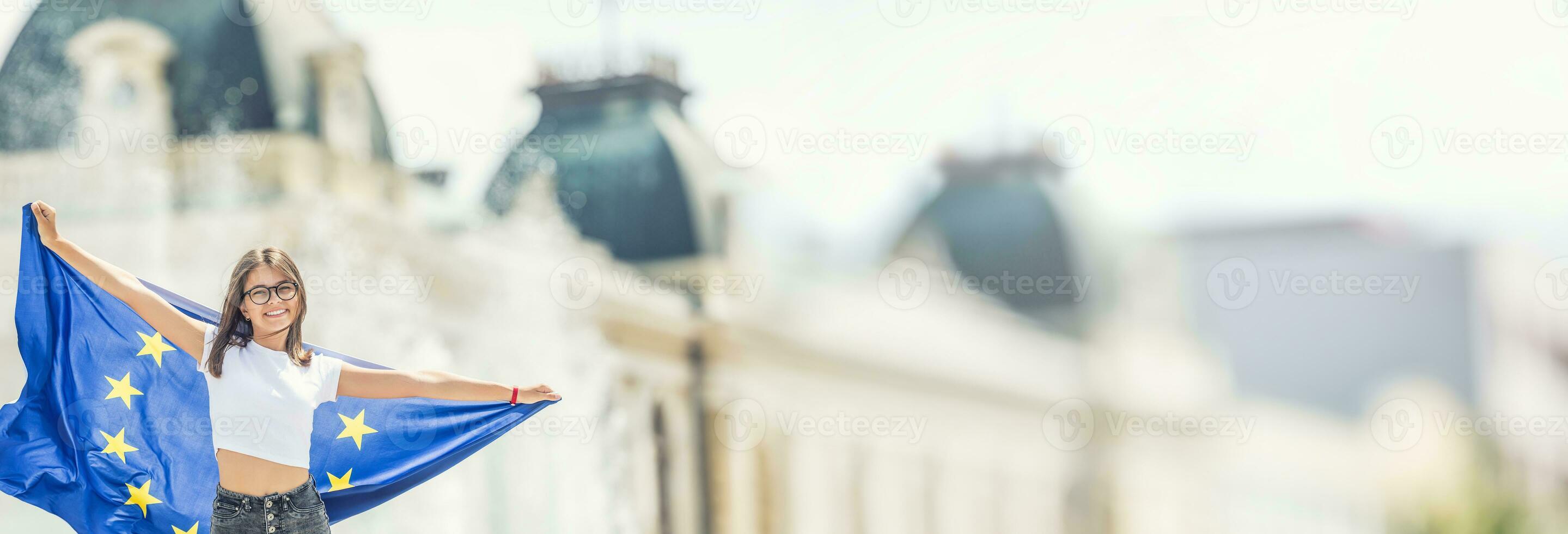 schattig gelukkig jong meisje met de vlag van de Europese unie in voorkant van een historisch gebouw ergens in Europa. foto