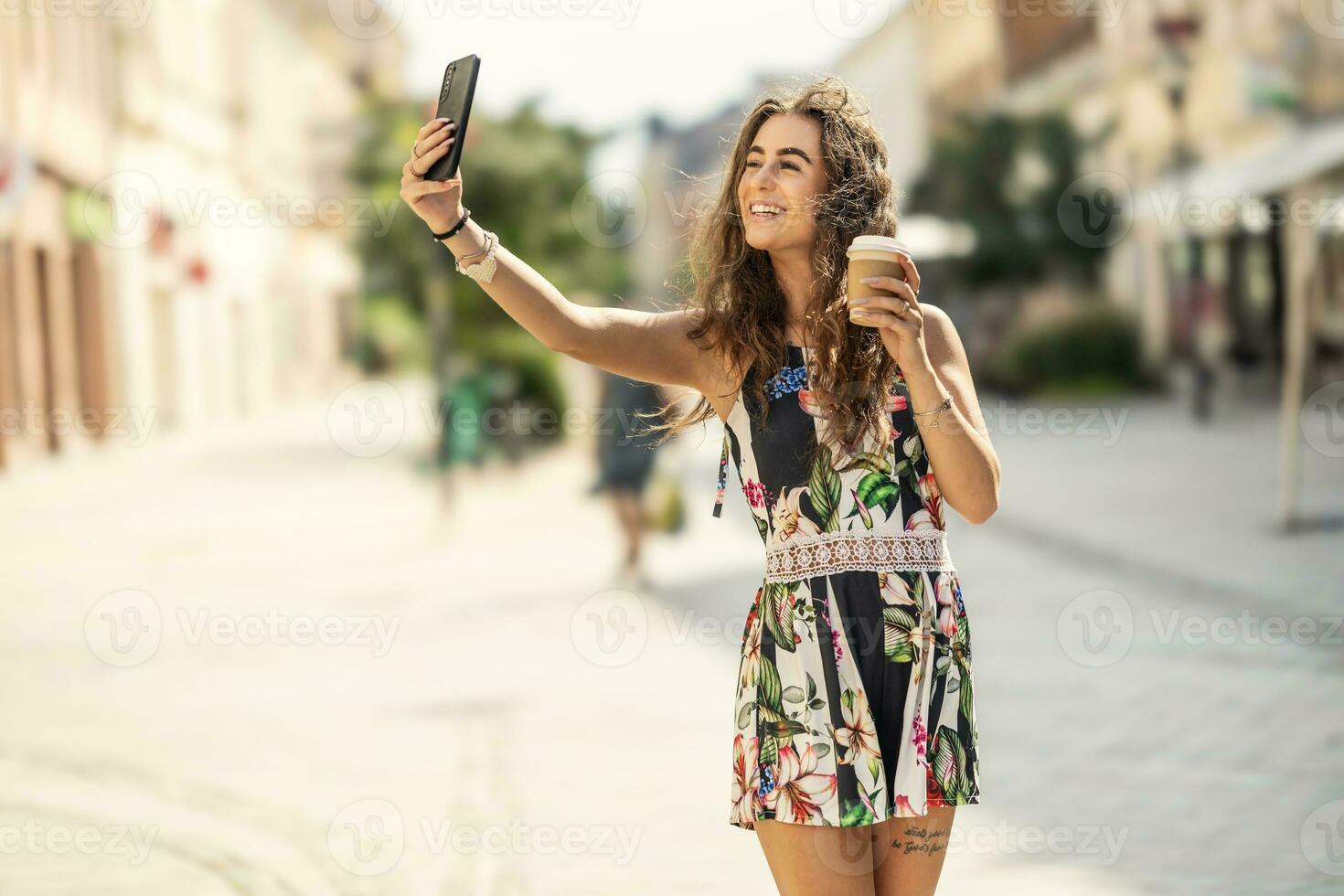 jong mooi glimlachen vrouw nemen selfie Holding meenemen koffie en wandelen in de stad foto