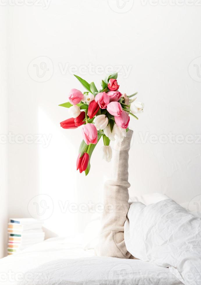 vrouw arm gestrekt van de deken met een boeket tulpen bouquet foto