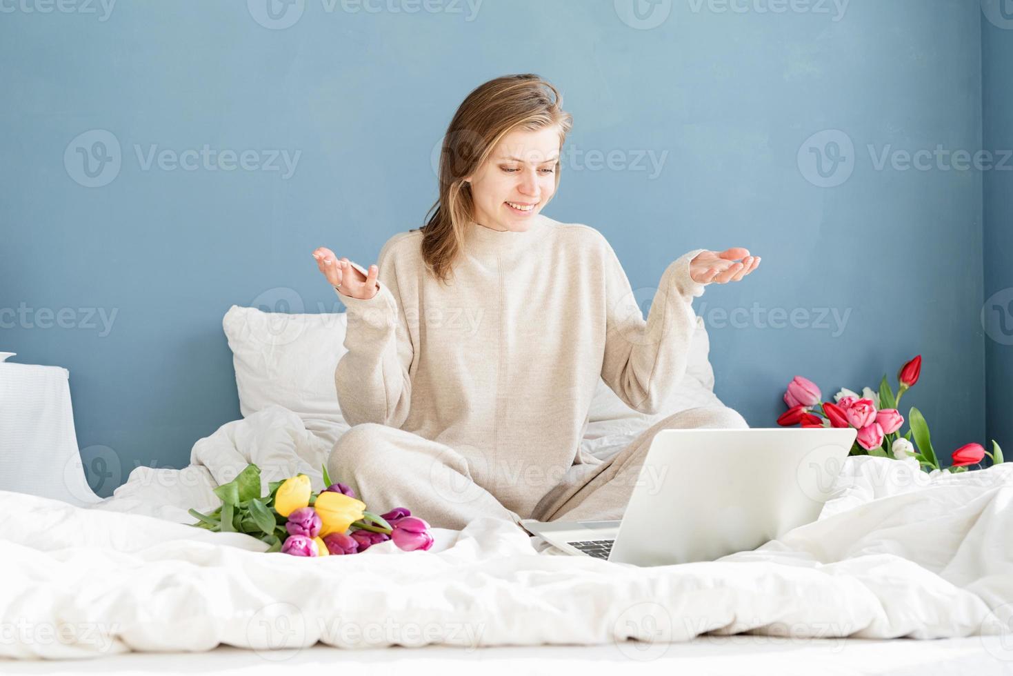 vrouw zittend op het bed chatten op laptop foto