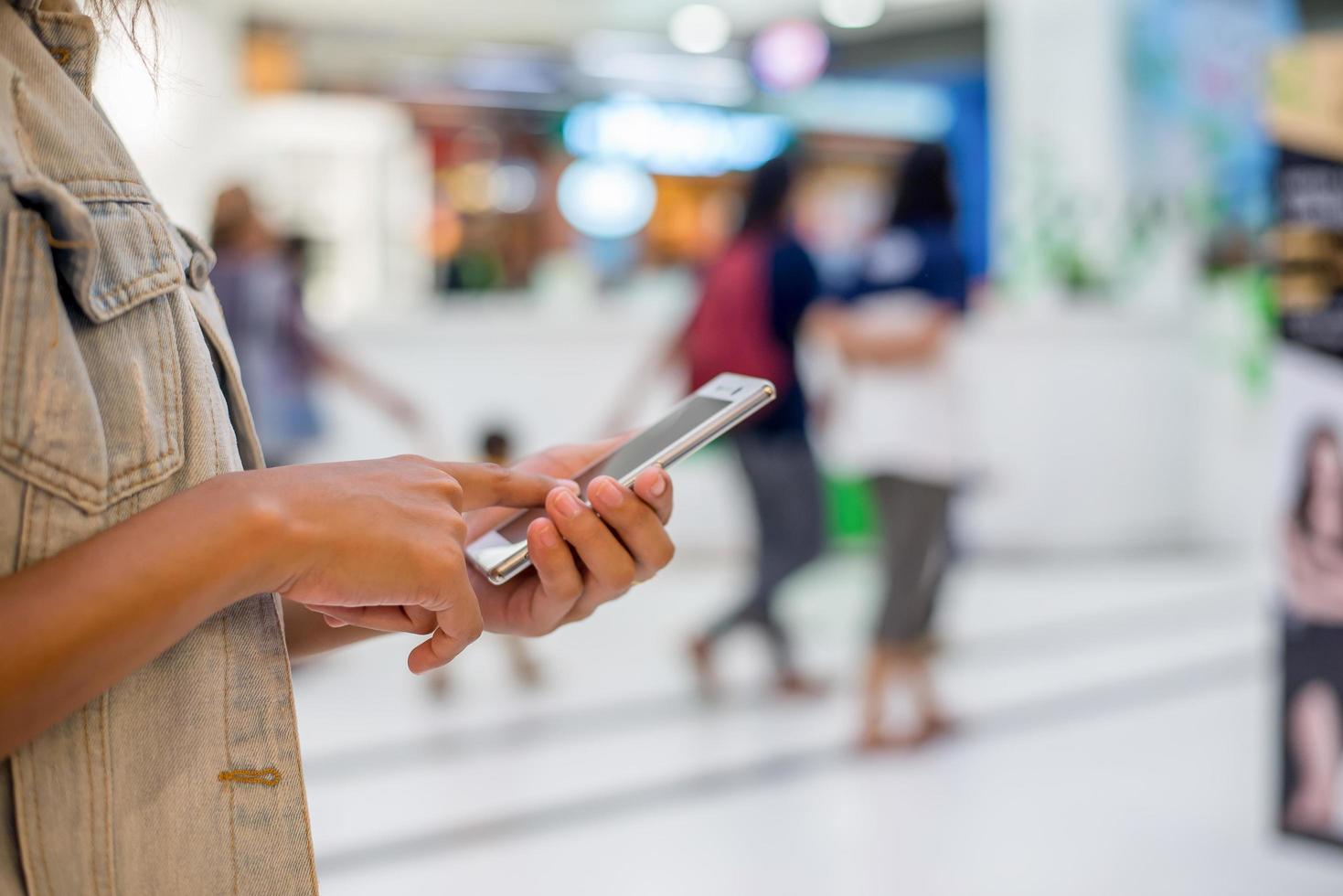 jonge vrouw hand met typende smartphone om te chatten in het winkelcentrum. foto