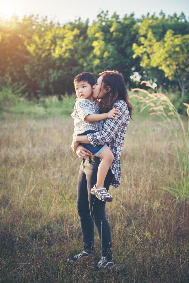 mama knuffelt haar kleine jongen die in het veld loopt. buitenshuis. foto