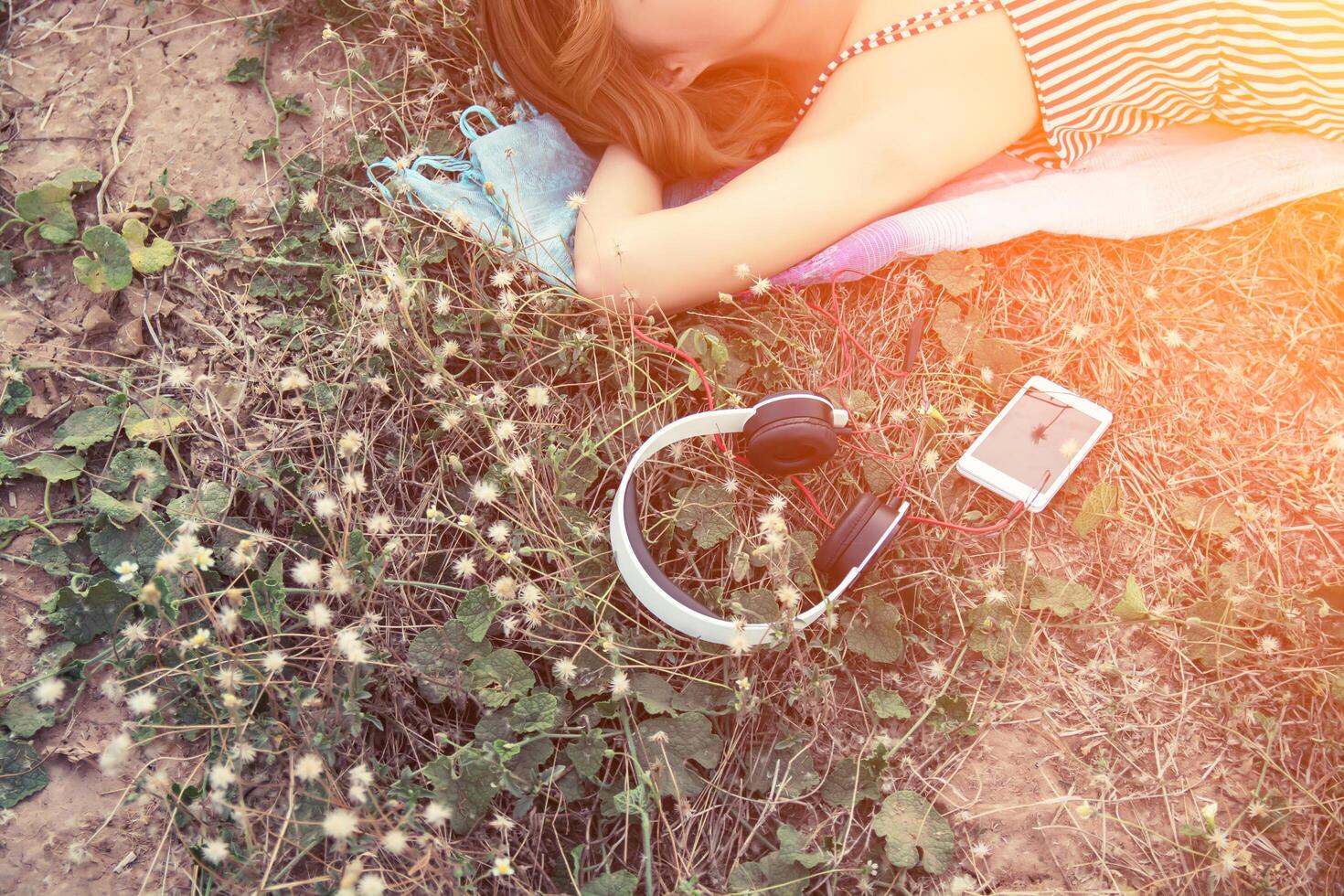 bovenaanzicht van een jonge vrouw die bijna een koptelefoon in het bloemenveld nadert foto