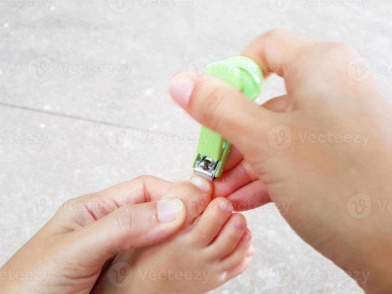 close-up aziatische moeder die de vingernagels van baby's voet knipt foto