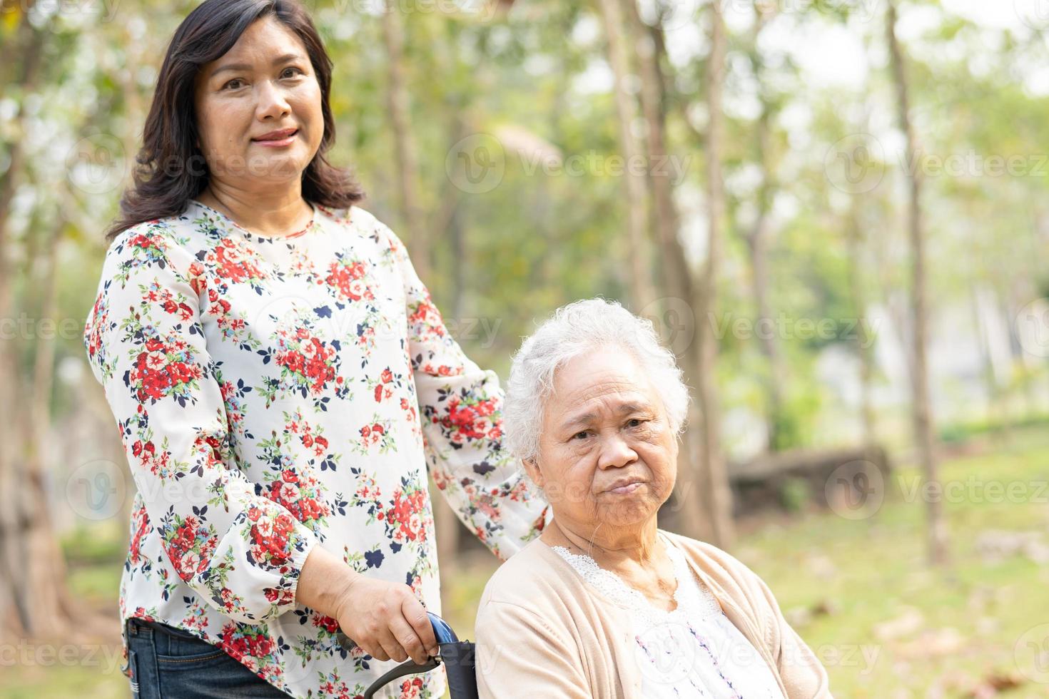 Aziatische senior vrouw patiënt met zorg op rolstoel in park foto