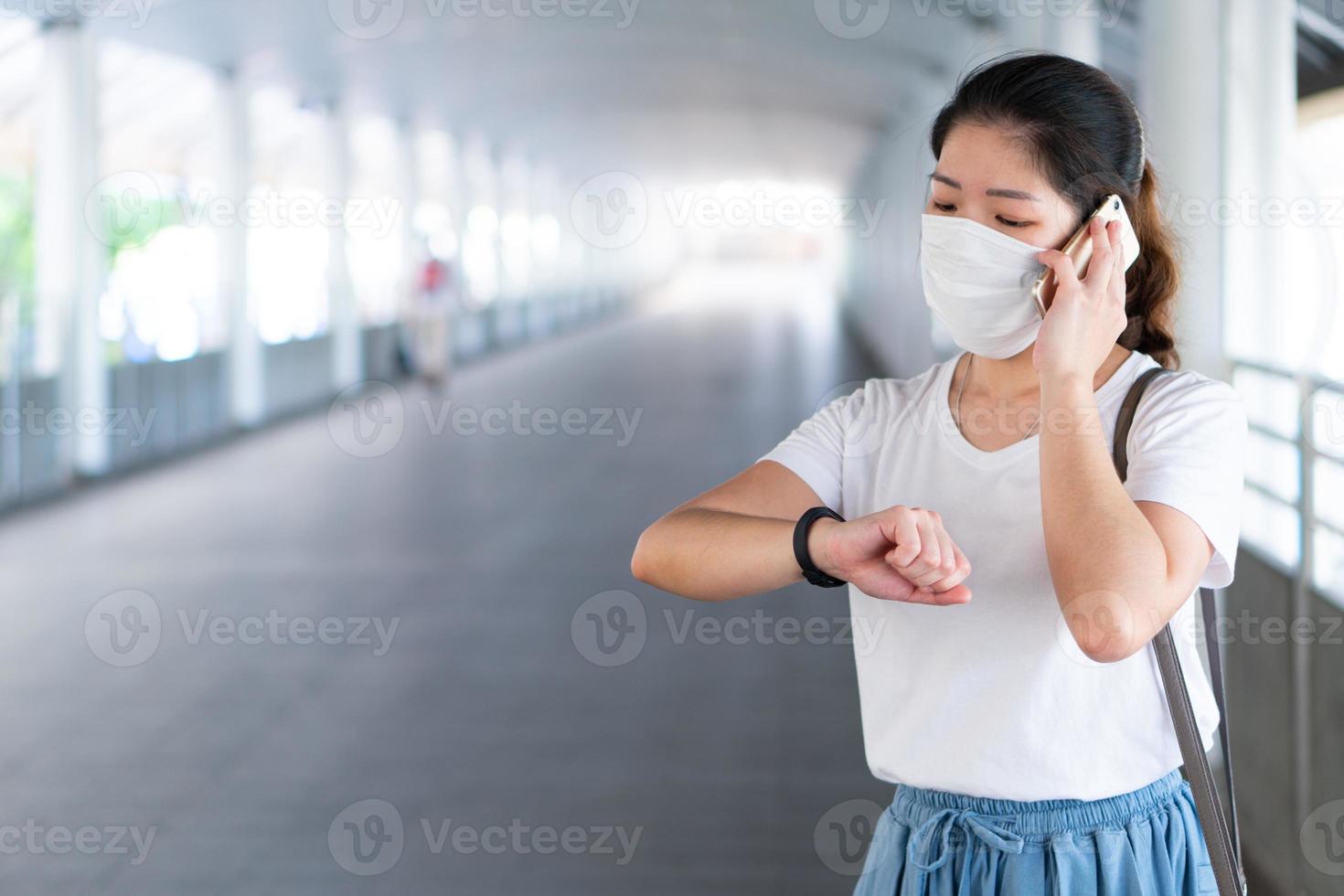 jonge vrouw met masker die smartphone gebruikt tijdens pandemie foto