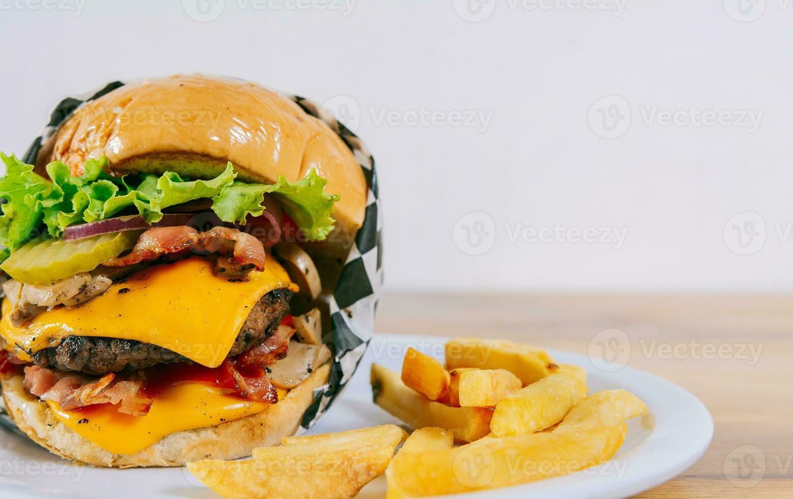 eigengemaakt hamburger met Frans Patat Aan een bord Aan houten tafel. groot cheeseburger met Patat geserveerd met kopiëren ruimte foto