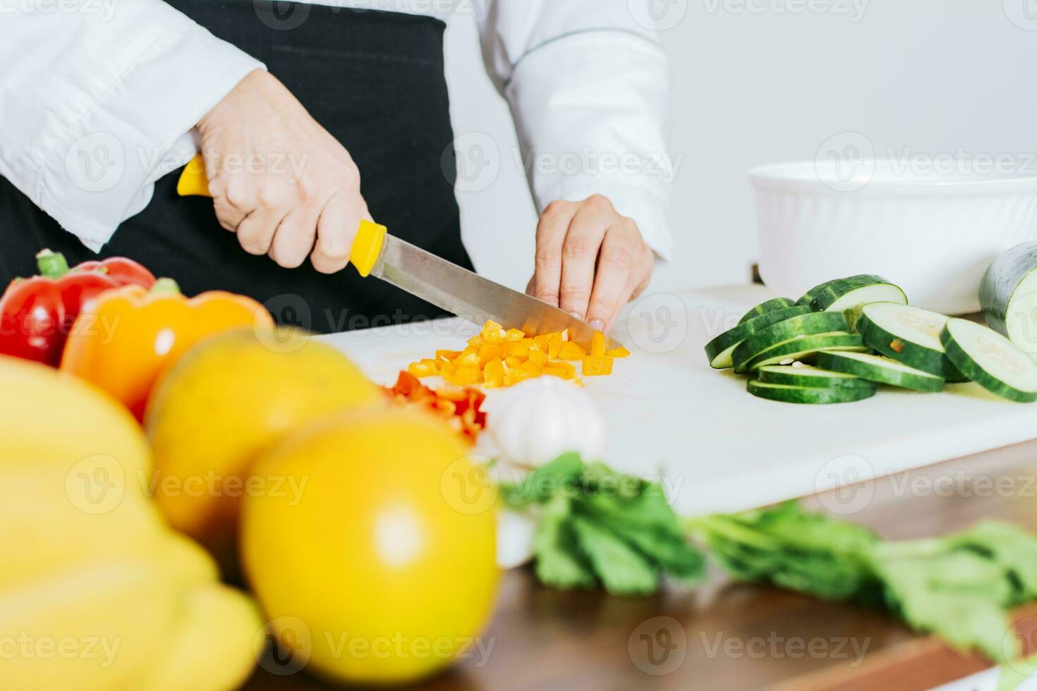 dichtbij omhoog van een vrouw chef snijdend groenten, handen van vrouw chef snijdend groenten, chef handen voorbereidingen treffen en snijdend groenten foto