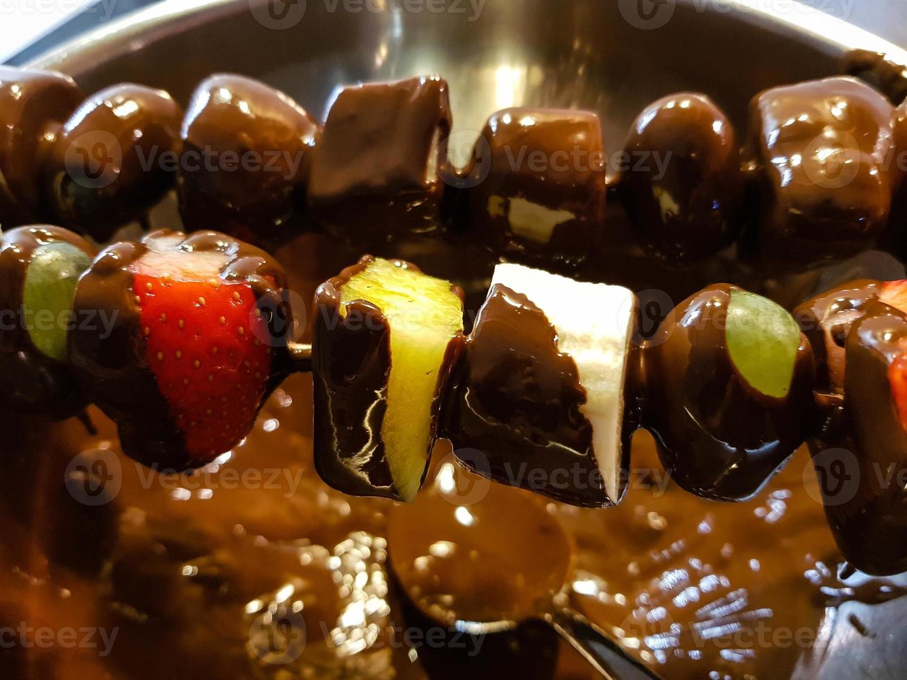 verschillende soorten fruit aan een spies omhuld met chocolade foto