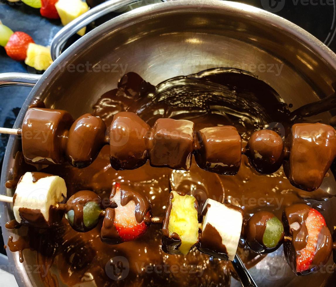 verschillende soorten fruit aan een spies omhuld met chocolade foto