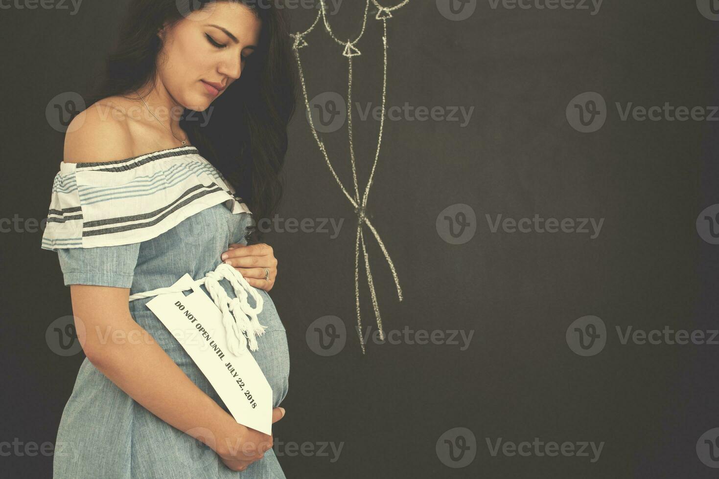 portret van zwanger vrouw in voorkant van zwart schoolbord foto