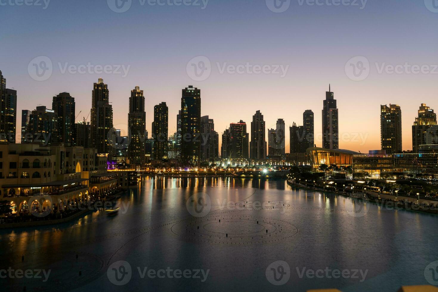 Dubai het zingen fonteinen Bij nacht meer visie tussen wolkenkrabbers. stad horizon in schemer modern architectuur in uae hoofdstad binnenstad. foto