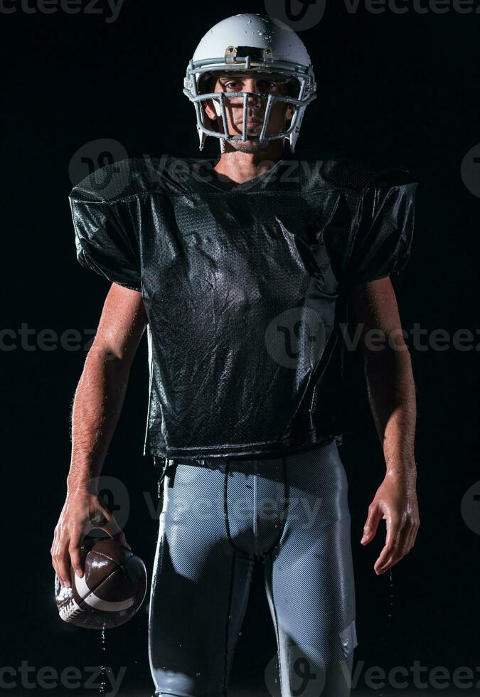 Amerikaans Amerikaans voetbal veld- eenzaam atleet krijger staand Aan een veld- houdt zijn helm en klaar naar Speel. speler voorbereidingen treffen naar rennen, aanval en partituur touchdown. regenachtig nacht met dramatisch mist, blauw licht foto