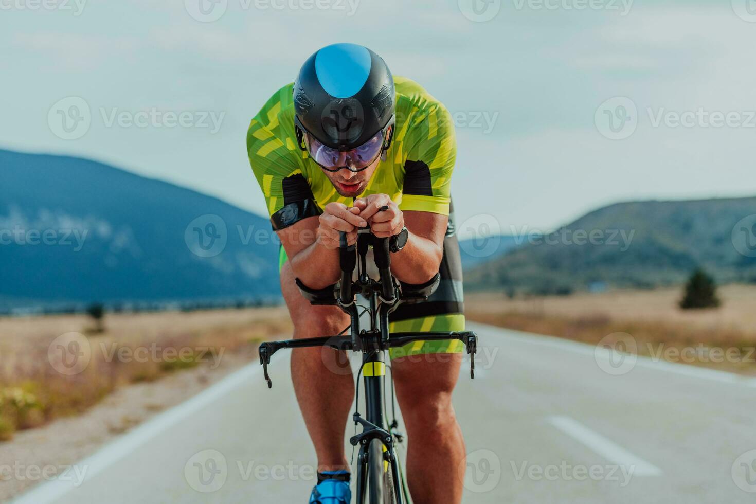 vol lengte portret van een actief triatleet in sportkleding en met een beschermend helm rijden een fiets. selectief focus foto