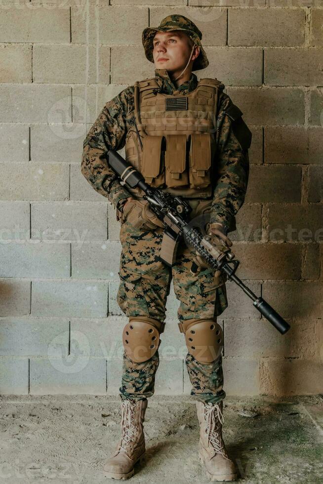 een soldaat in uniform staat in voorkant van een steen muur in vol oorlog uitrusting voorbereidingen treffen voor strijd foto