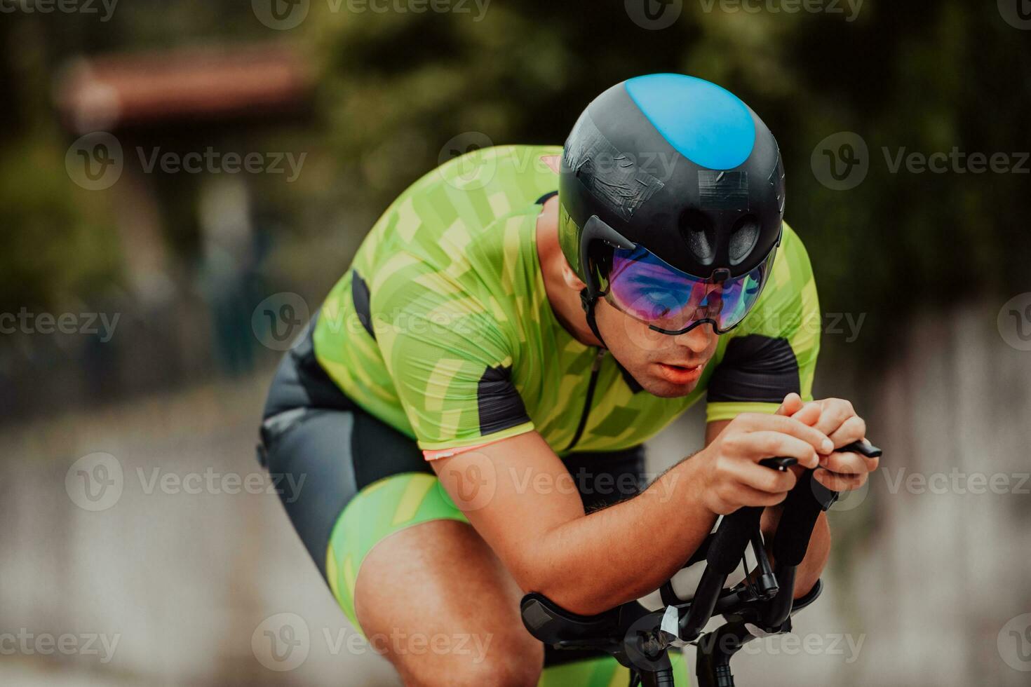 dichtbij omhoog foto van een actief triatleet in sportkleding en met een beschermend helm rijden een fiets. selectief focus