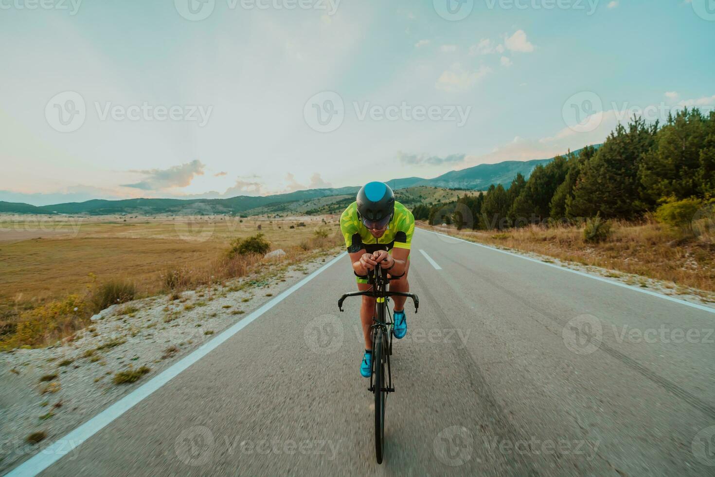 vol lengte portret van een actief triatleet in sportkleding en met een beschermend helm rijden een fiets. selectief focus foto