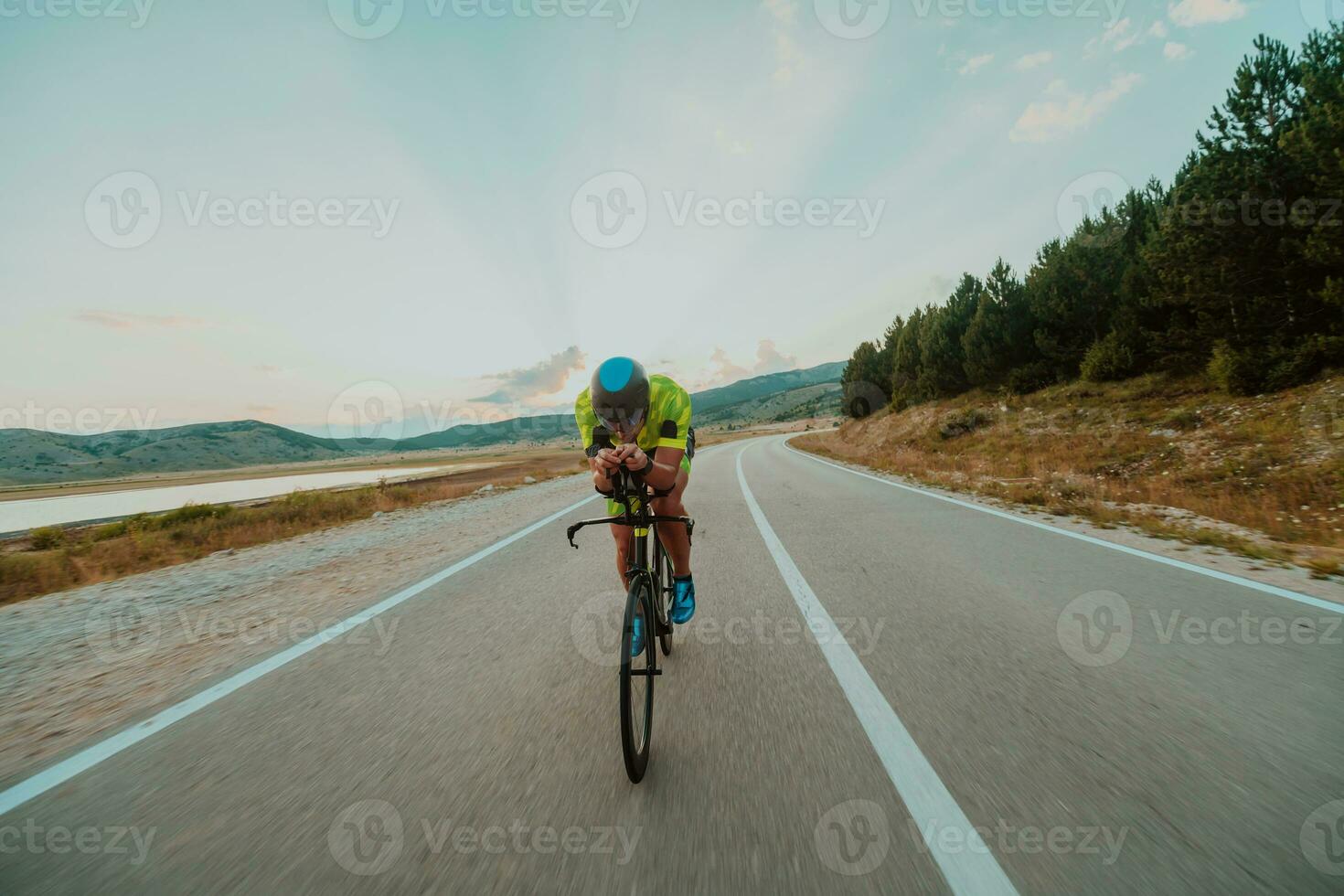 vol lengte portret van een actief triatleet in sportkleding en met een beschermend helm rijden een fiets. selectief focus foto