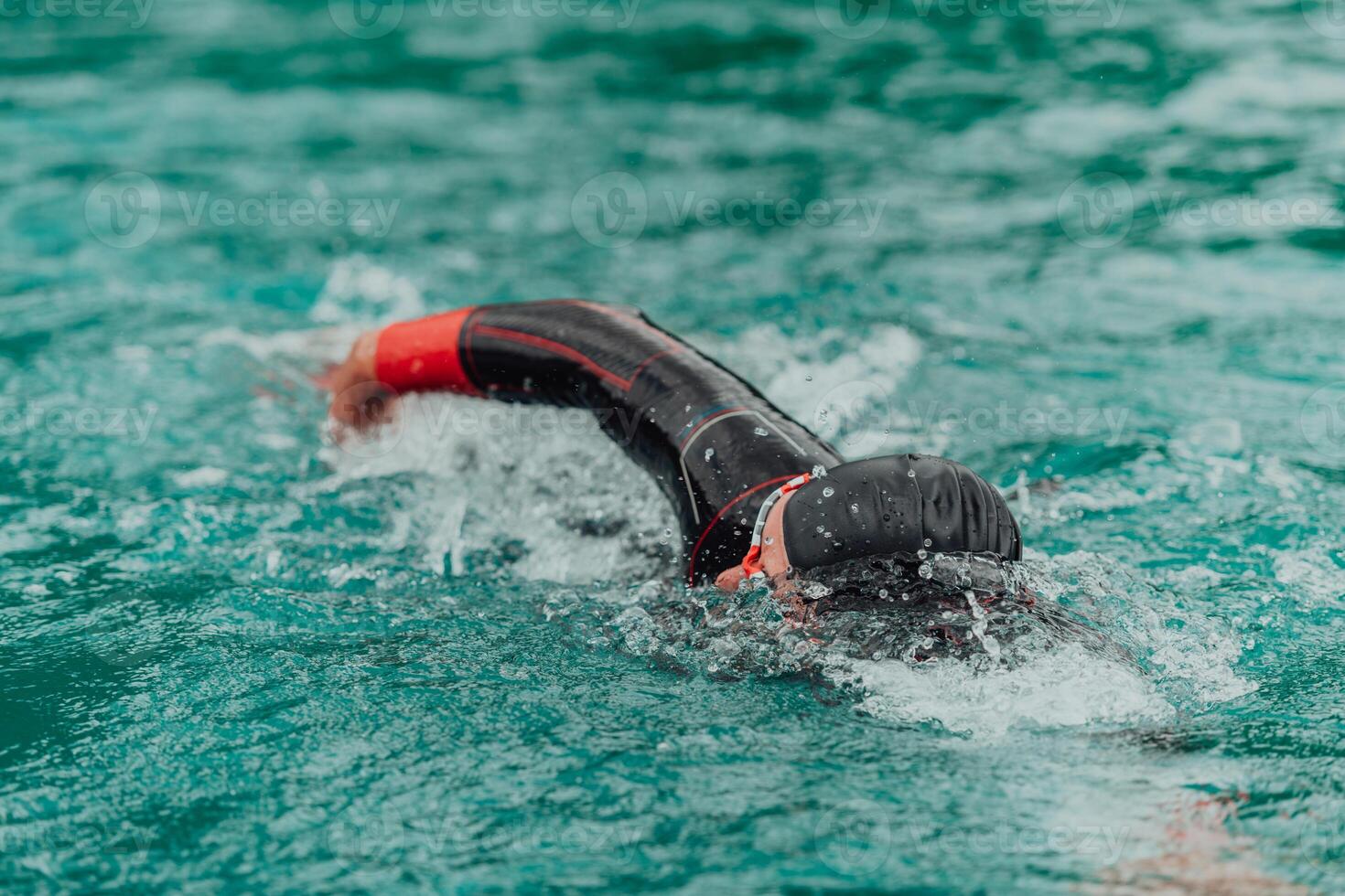 een triatleet in een professioneel zwemmen pak treinen Aan de rivier- terwijl voorbereidingen treffen voor olympisch zwemmen foto