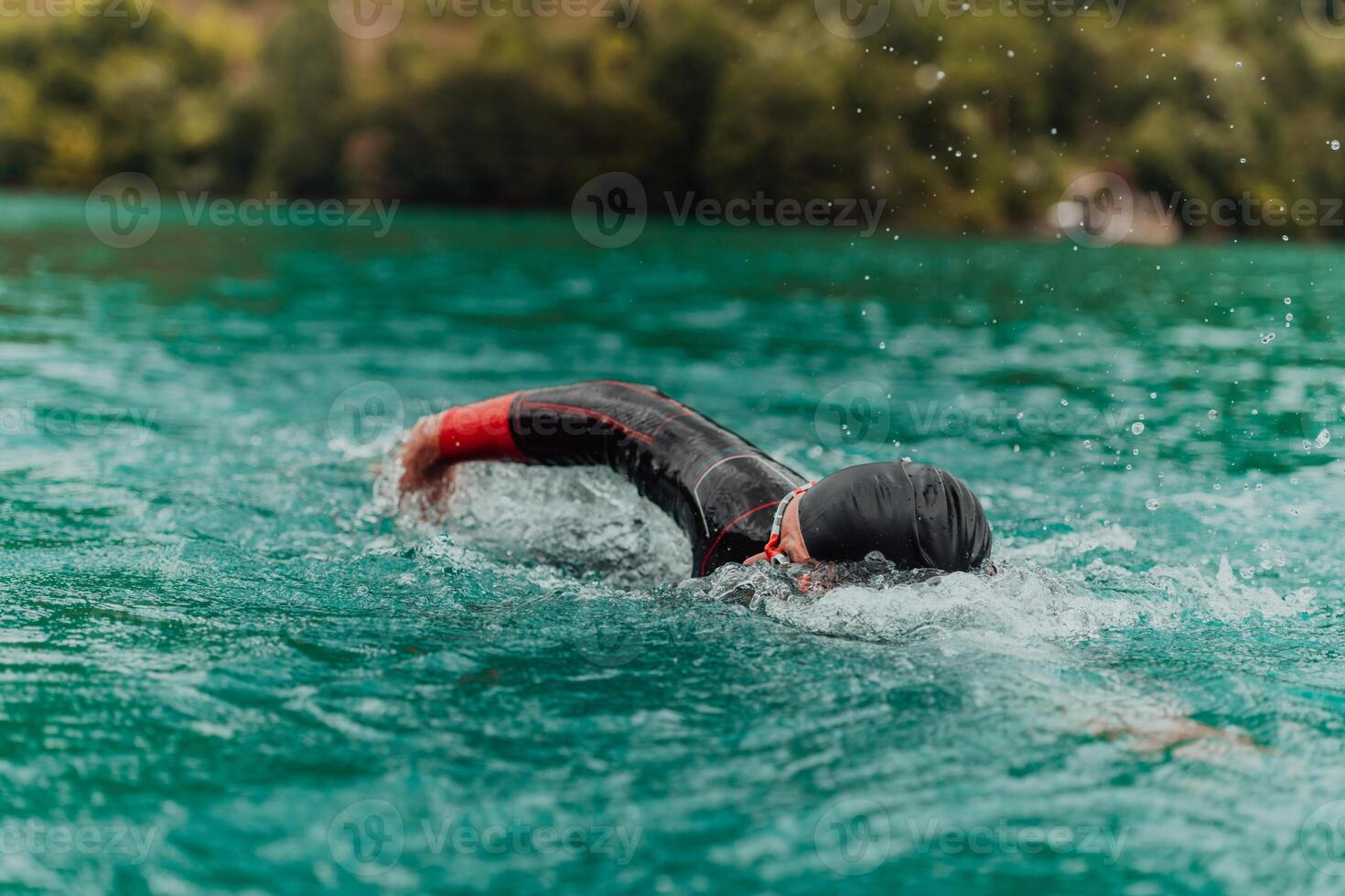 een triatleet in een professioneel zwemmen pak treinen Aan de rivier- terwijl voorbereidingen treffen voor olympisch zwemmen foto