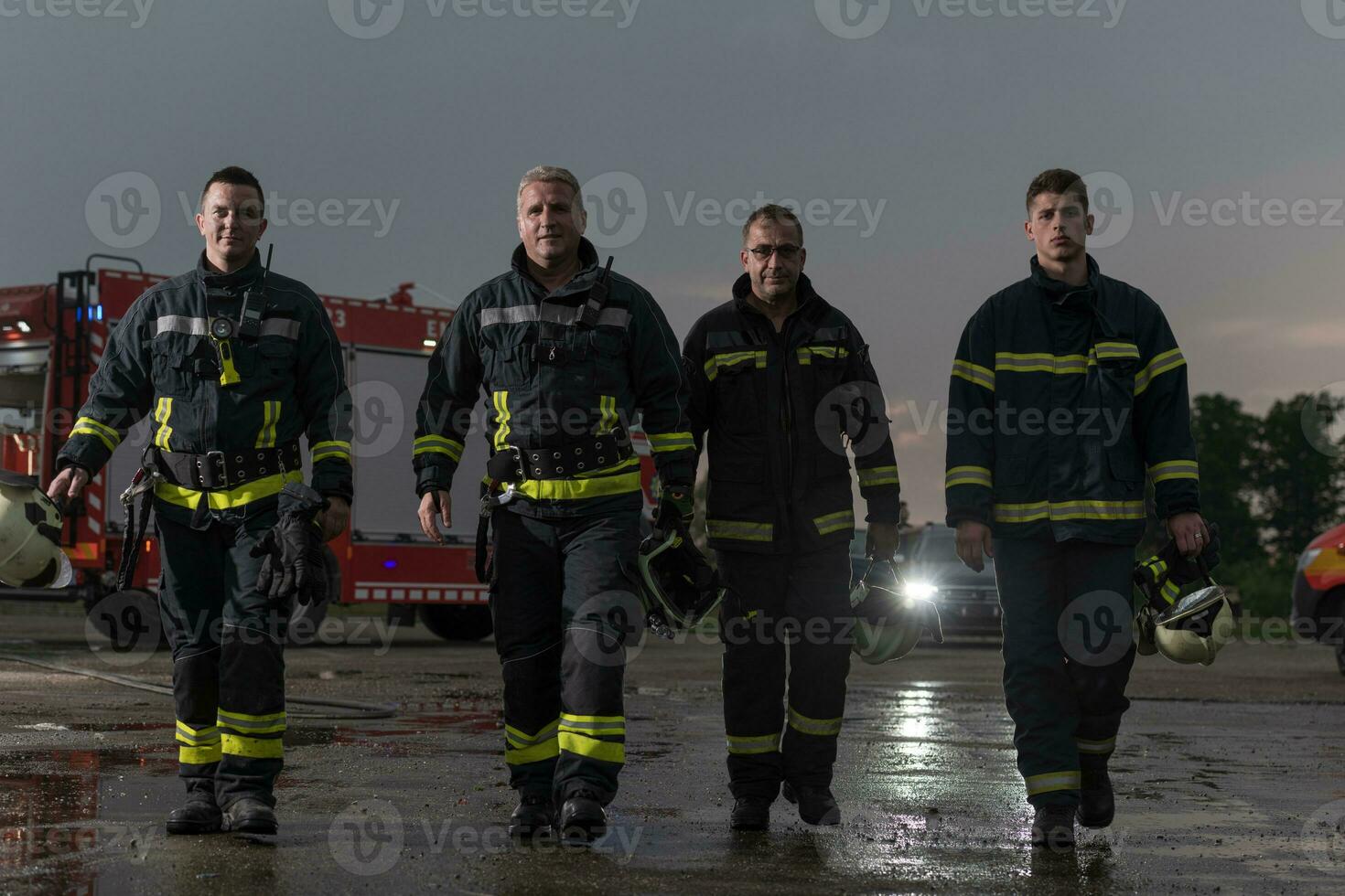 dapper brandweerlieden team wandelen naar de camera. in achtergrond paramedici en brandweer redden team strijd brand in auto ongeluk, verzekering en opslaan volkeren leeft concept. foto