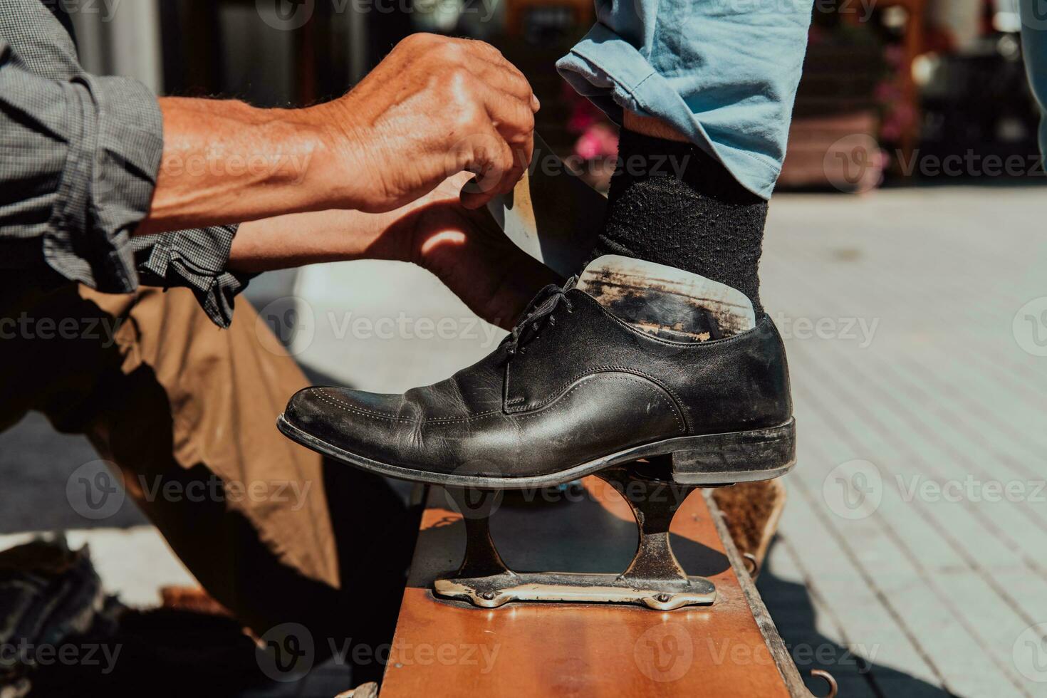 een oud Mens hand- polijsten en schilderij een zwart schoen Bij straat foto