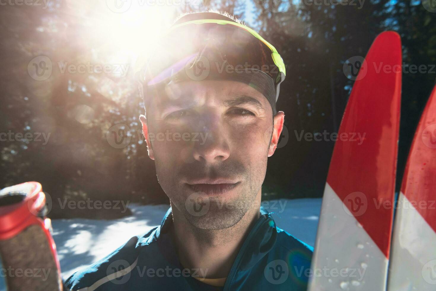 portret knap mannetje atleet met kruis land skis in handen en stofbril, opleiding in besneeuwd Woud. gezond winter levensstijl concept. foto