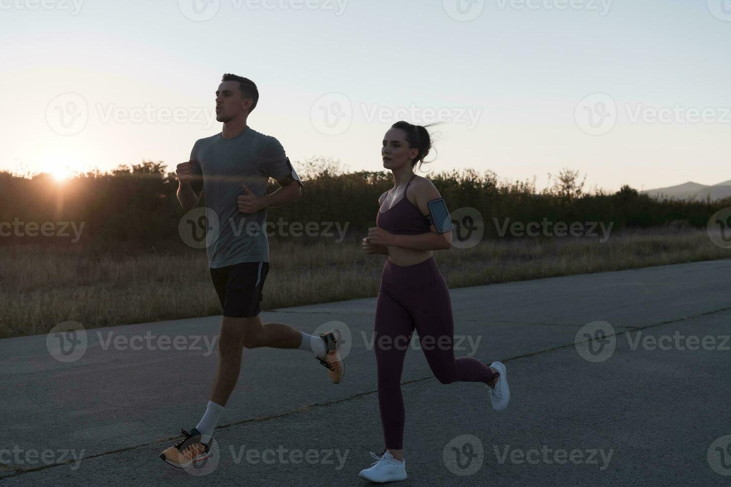 gezond jong paar jogging in de stad straten in de vroeg ochtend- met een mooi zonsopkomst in de achtergrond. foto