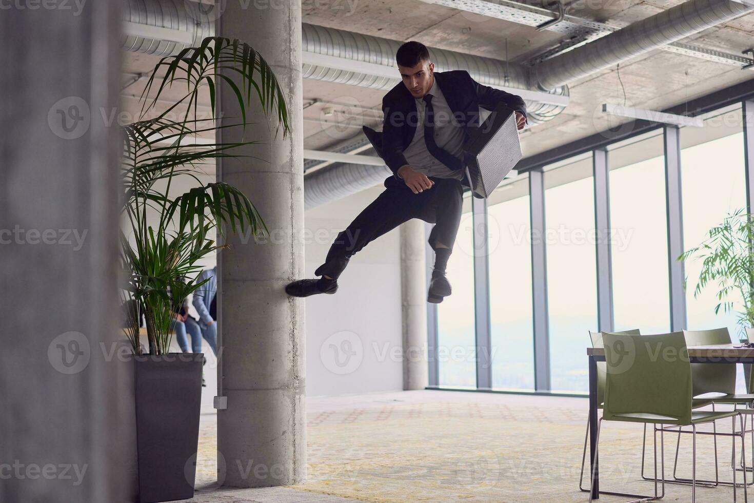 in de modern kantoor, een zakenman met een aktentas boeit iedereen net zo hij presteert spannend antenne acrobatiek, tarten zwaartekracht met zijn gedurfd sprongen en presentatie van zijn behendigheid met adembenemend showmanschap. foto