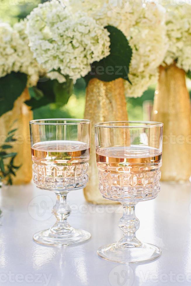 rose wijn in glazen. rose wijn op gouden flessen achtergrond foto